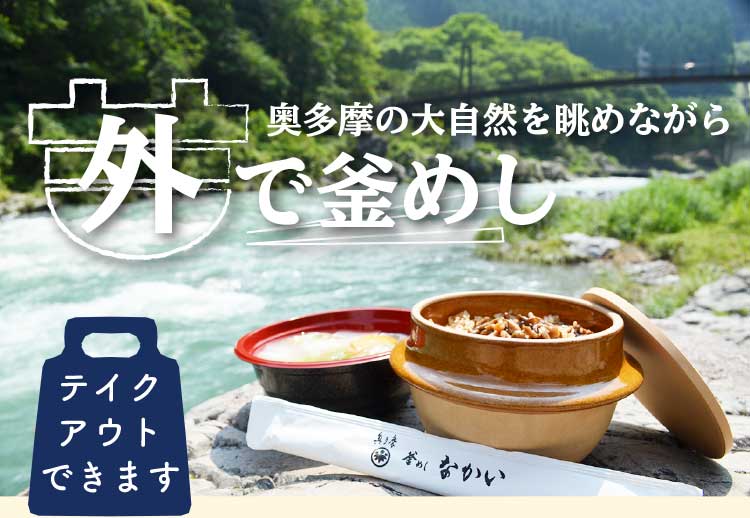 つり橋の見える川沿いの岩の上に、釜めし、水炊きがおいしそうに並んでいます。